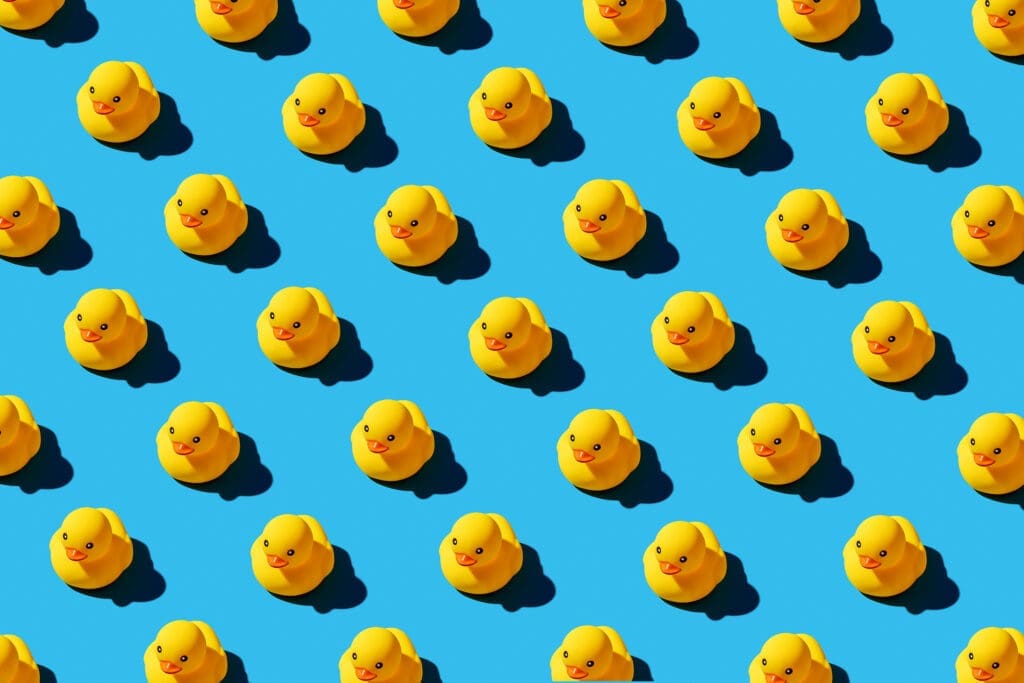 yellow rubber ducks on a blue background all aligned in same direction "Ducks in a row" Thom Baker Consultancy